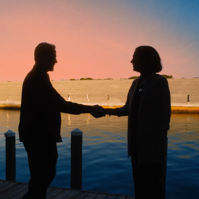 Handshake silhouette between contractor and homeowner on a finished Cape Coral dock at sunset